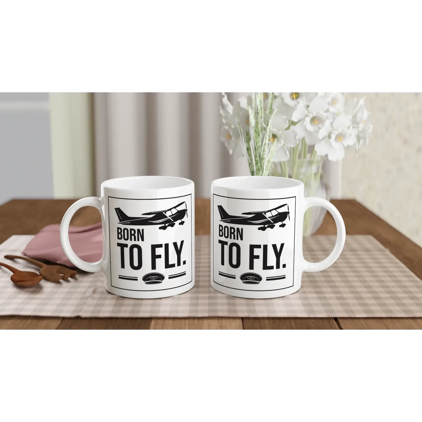 Tassen mit dem Aufdruck „Born to fly“ für Piloten und Flugbegeisterte auf einem Holztisch.