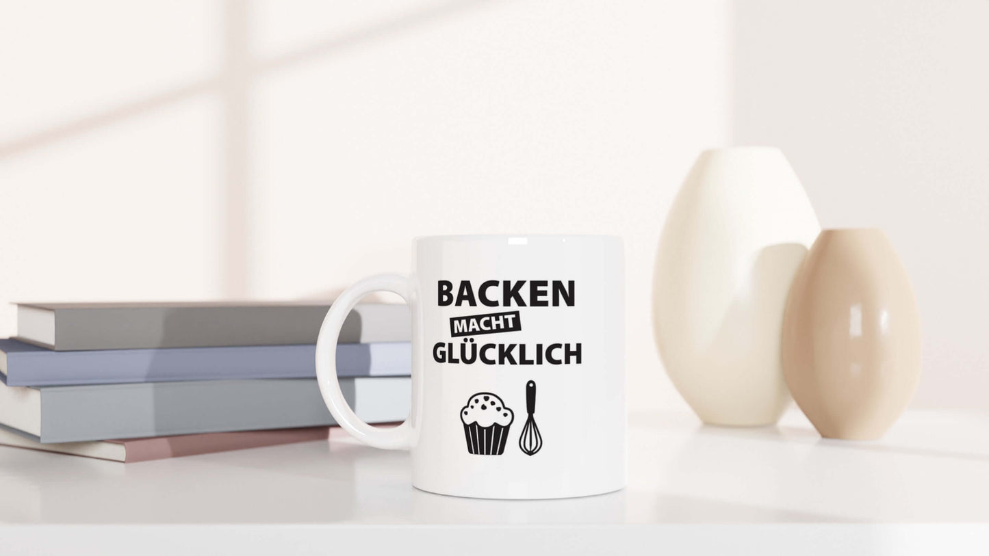 "Backen macht glĂźcklich"-Tasse dekorativ platziert mit Vasen und BĂźchern im Hintergrund