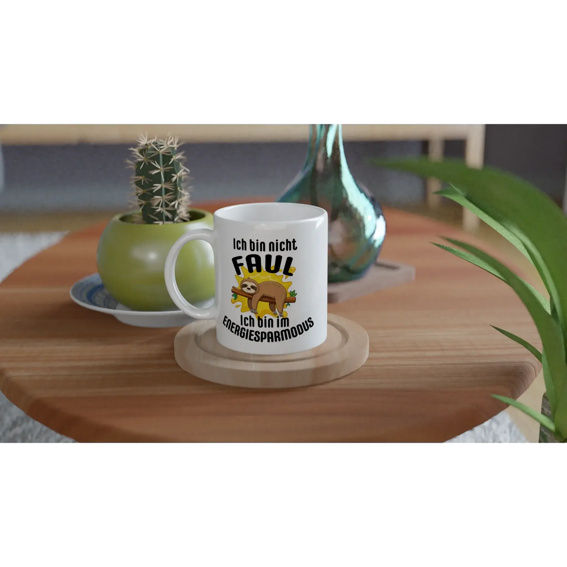 Eine Tasse mit Herz's Humorvoller Kaffeebecher „Ich bin nicht faul“ ziert den Holztisch und hebt ein Cartoon-Faultier mit „Ich bin nicht faul, ich bin im Energiesparmodus“ hervor. In der Nähe vervollständigen eine grüne Vase und ein kleiner Kaktus diese bezaubernde Szene – ideal für einen entspannten Lebensstil.