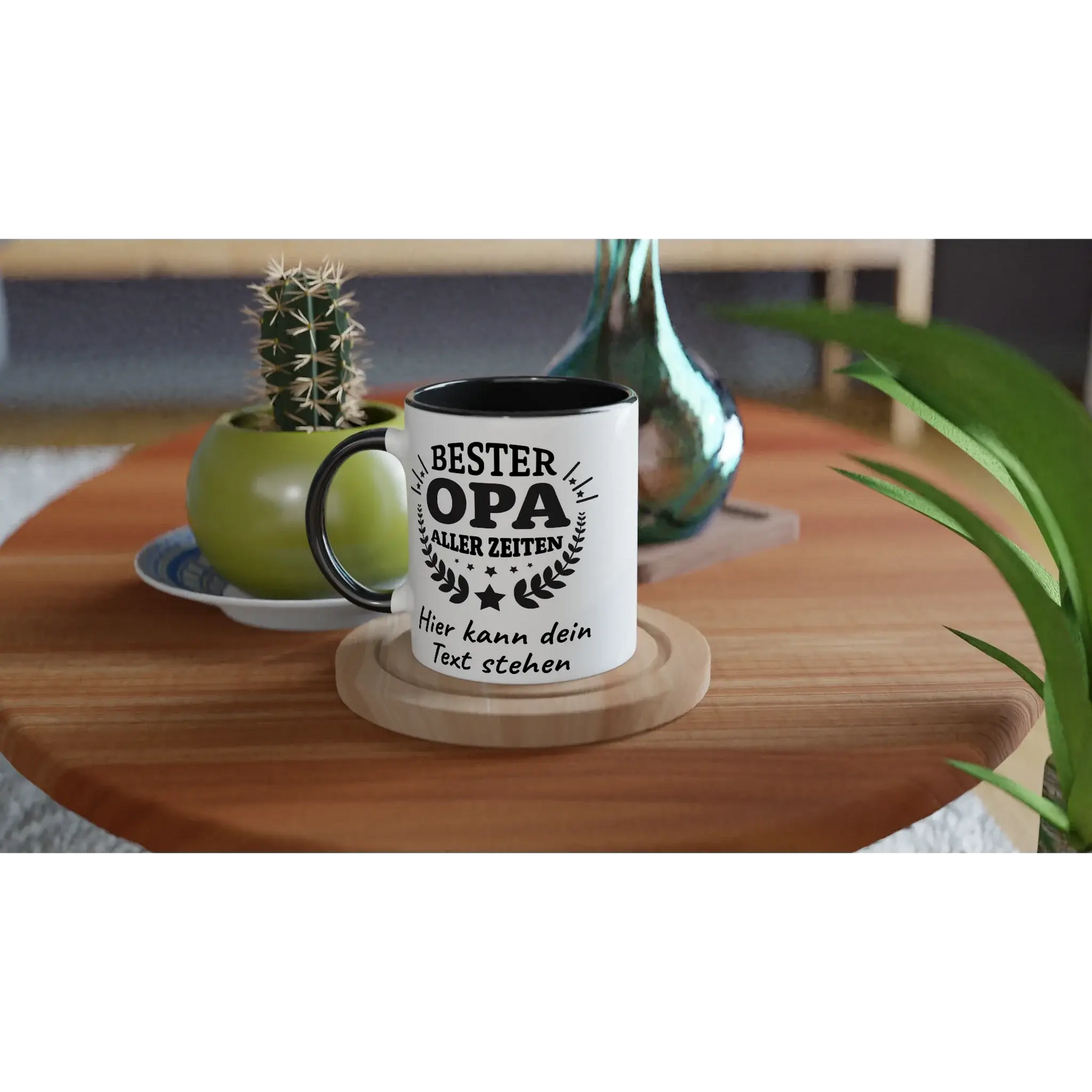 The 🏆 Tasse ‚Bester Opa aller Zeiten‘ – Mit persönlicher Widmung by Tasse mit Herz, ideal as a Geschenk, sits on a wooden table near a potted cactus and glass bottle. This personalisierte Tasse is perfect for appreciating your Opa.