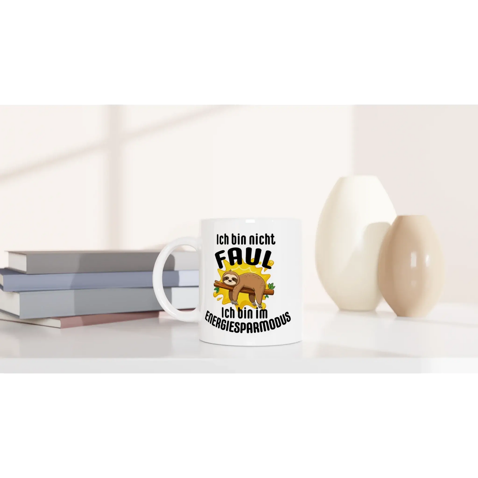 Der „Humorvoller Kaffeebecher“ von Tasse mit Herz enthält einen deutschen Text und ein Cartoon-Faultier mit der Aufschrift „Ich bin nicht faul, ich bin im Energiesparmodus“. Perfekt für einen entspannten Lebensstil, steht er auf dem Tisch neben gestapelten Büchern und dekorativen Vasen.