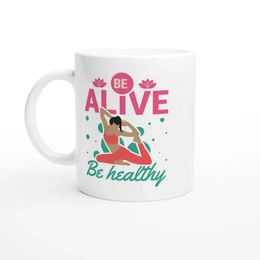 Die Achtsamkeits-Tasse „Be Alive, Be Healthy“ von Tasse mit Herz ist eine weiße Tasse mit einer Person in Yoga-Pose, grünen Punkten und rosa Lotusblüten. Sie eignet sich ideal als Yoga-Geschenk oder Gesundheits-Accessoire.