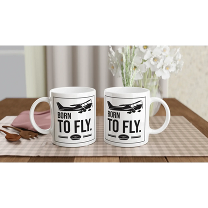 Tassen mit dem Aufdruck „Born to fly“ für Piloten und Flugbegeisterte auf einem Holztisch.