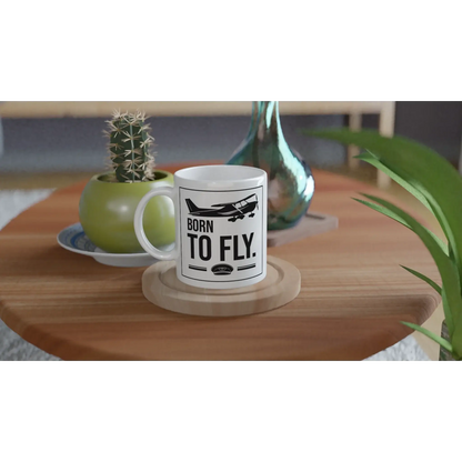 Tasse "Born to fly" auf einem Tisch, ideal für Piloten und Flugzeugfans, mit modernem Design.